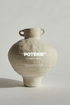 a white vase sitting on top of a table next to a gray wall with the words potterie written on it