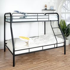 a bunk bed with white sheets and pillows on it in a room next to a potted plant