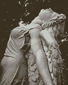 a black and white photo of a woman's head resting on an angel statue