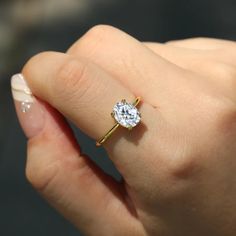 a woman's hand holding an engagement ring with a diamond on the middle finger