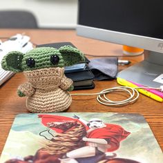 a crocheted baby yoda doll sitting on top of a desk