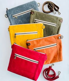 four different colored purses sitting next to each other on top of a white surface