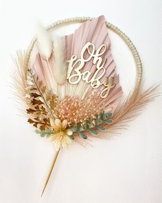 a pink fan with the word oh baby written on it next to flowers and feathers