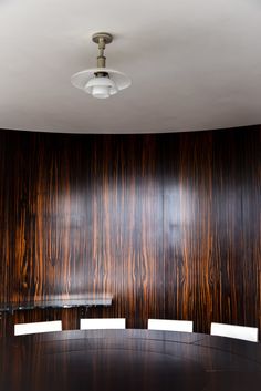 an empty conference room with wood paneling on the wall and round table in front