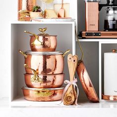 copper pots and pans are stacked on shelves in a kitchen with other items nearby