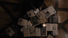 an overhead view of several open books on the floor with a candle in between them