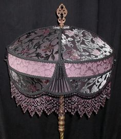 a pink and black lace lamp shade on a wooden stand with a metal base,