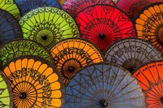 many colorful umbrellas are stacked up together