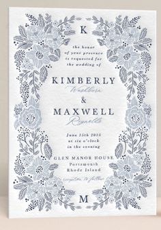 a wedding card with blue flowers and leaves on the front, in an ornate frame