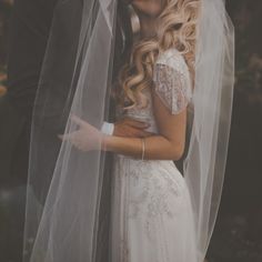 a bride and groom standing under a veil