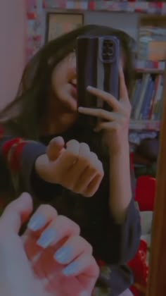 a woman taking a selfie with her phone in front of a book shelf filled with books