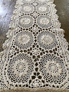 a table runner made out of crocheted doily on top of a wooden floor