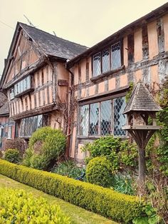 an old house with lots of windows and bushes