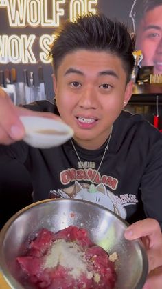 a man holding a spoon over a bowl filled with food