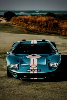 a blue sports car parked on top of a grass covered field