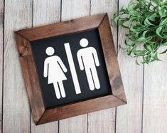 a wooden frame with a sign that says man and woman on it next to a potted plant