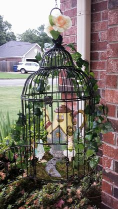 a birdcage with flowers on the outside of it sitting in front of a brick wall