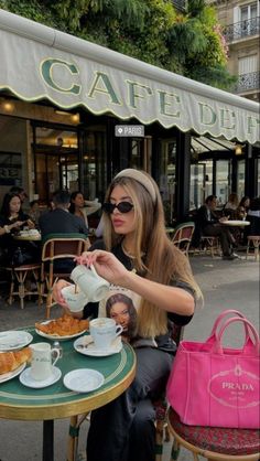 a woman sitting at a table with food in front of her and a pink bag