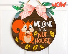 a wooden sign that says welcome to the nut house with a cartoon squirrel holding an acorn