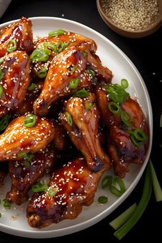 chicken wings with sesame seeds and green onions on a white plate