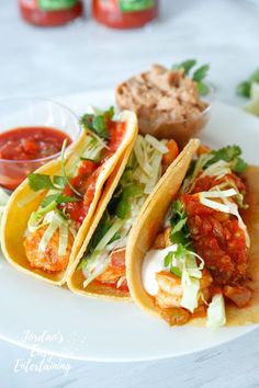 three tacos on a plate with salsa and cole slaw