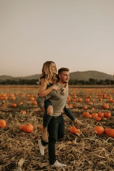 a man carrying a woman in a field full of pumpkins