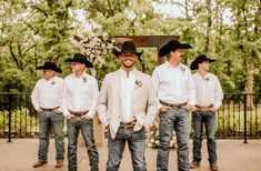 a group of men wearing cowboy hats standing next to each other in front of a fence