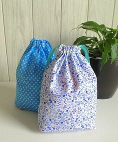 two blue and white bags sitting next to each other on top of a table near a potted plant