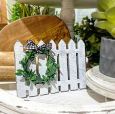 a white picket fence with a wreath on it and a potted plant in the background