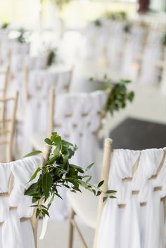 chairs with white sashes and greenery tied to them