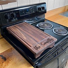 a wooden cutting board sitting on top of an electric stove in a kitchen with wood flooring