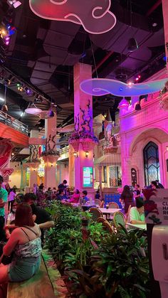 people are sitting at tables in a brightly lit restaurant with pink and blue lighting on the ceiling