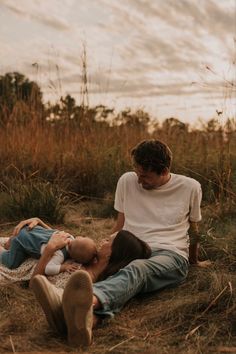 a man and woman are sitting on the ground with their heads touching each other as they cuddle