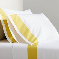 two white and yellow pillows sitting on top of a bed next to a pillow case