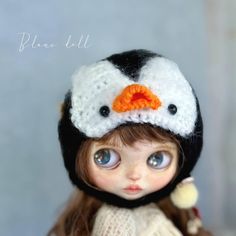 a close up of a doll wearing a knitted hat with a penguin on it