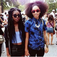 two young women walking down the street with their hands in each other's pockets