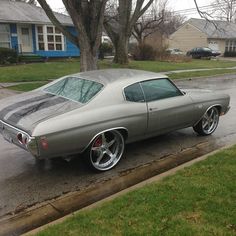 a silver car parked on the side of a road next to a tree and grass