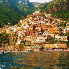 a small boat is in the water near a city on a mountain side with many buildings