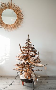 a christmas tree made out of driftwood in front of a mirror and sunburst