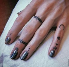 a woman's hand with two small tattoos on her fingers and the other finger