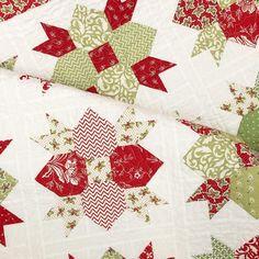 a close up of a quilt with red and green stars on it