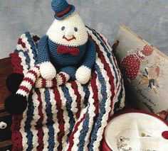 a crocheted stuffed animal sitting on top of a blanket next to an open book