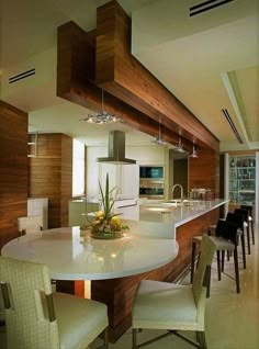 a kitchen with a center island surrounded by white chairs and counter tops, next to a dining room table