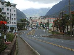 a city street with mountains in the background and cars driving on it's side