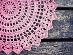 pink crocheted doily sitting on top of a wooden table