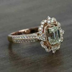 a fancy engagement ring with an emerald center surrounded by white and brown diamonds on a wooden surface