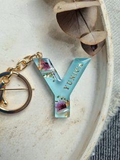 a keychain with the letter y on it sitting next to a flower arrangement