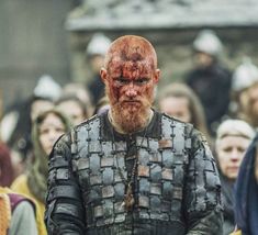 a man with blood on his face standing in front of a large group of people