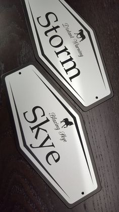 two white street signs sitting on top of a wooden table