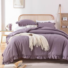 a bed with purple sheets and pillows in a room